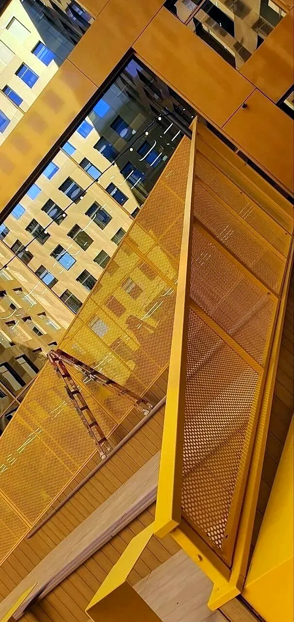 Yellow perforated balustrade along a stair, seen from above