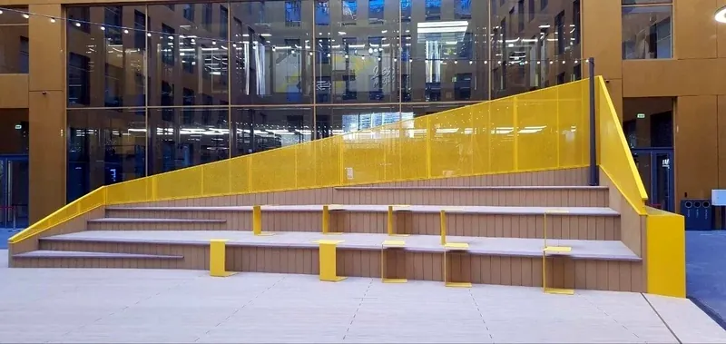 Amphitheatre with yellow perforated steel balustrades in a courtyard