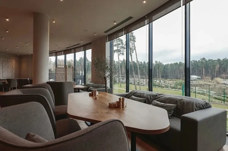Grey booth sofas and armchairs by a glass wall facing the woods
