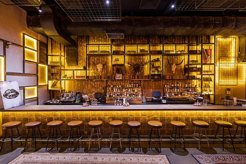 Bar back wall with backlit metal frames and shelving