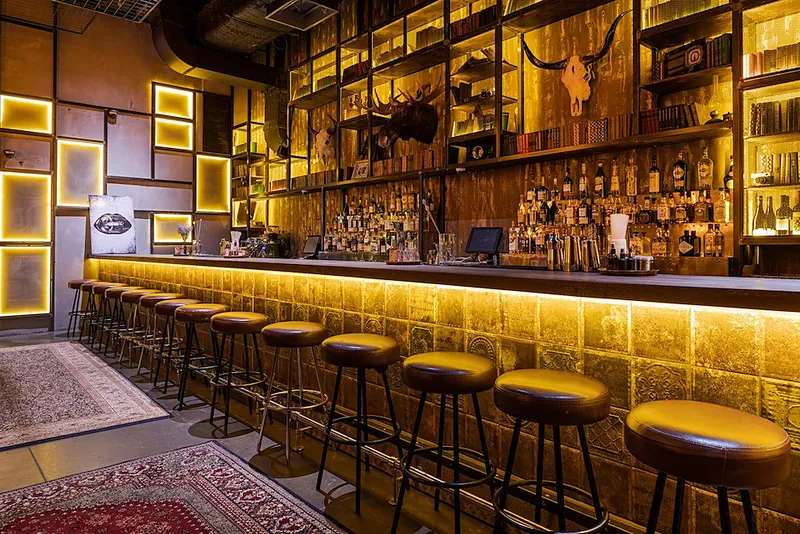 Long bar counter with leather stools and backlit metal frames