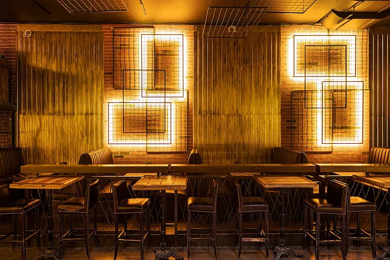 Backlit metal wall frames above banquette seating