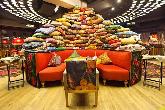 Orange booth sofas under a tower of embroidered cushions