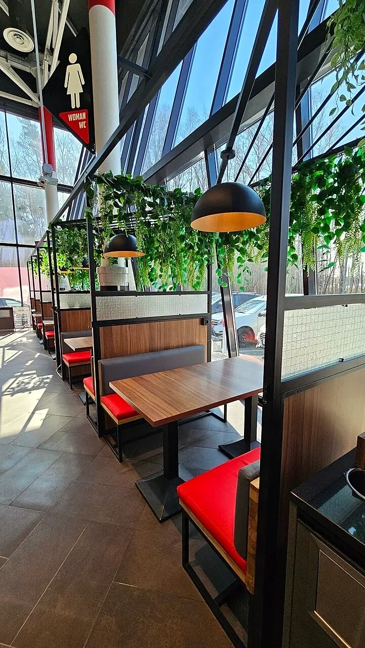 Booth sofas with red seats and black steel partitions by a glass facade