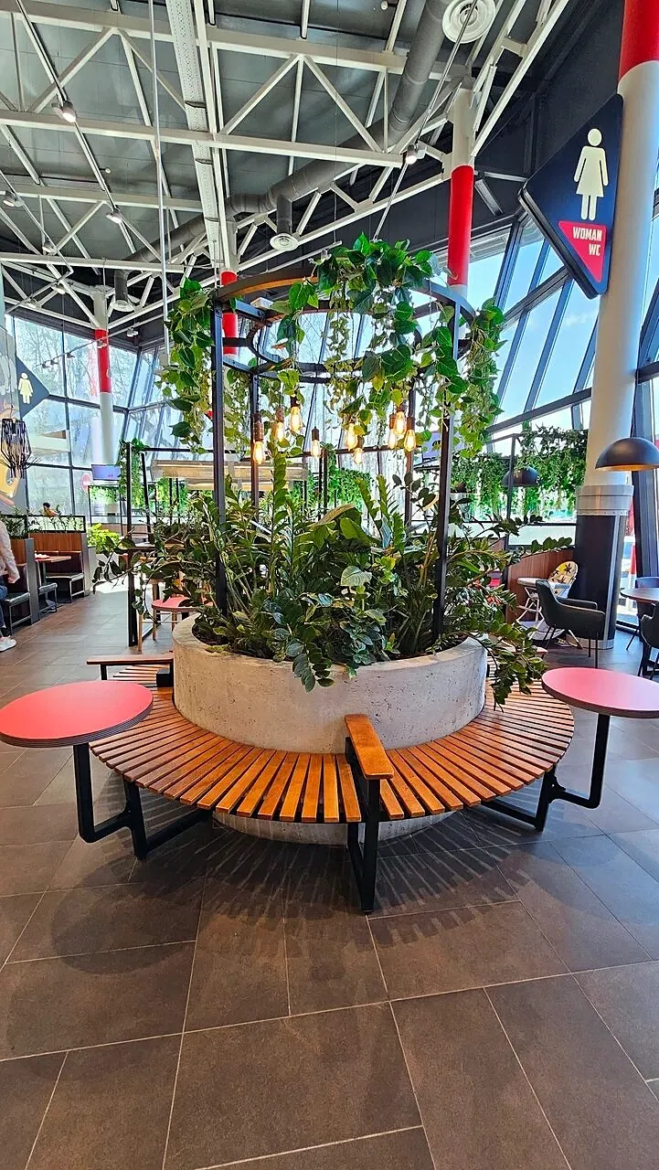 Round slatted bench around a planter in a fuel station food court