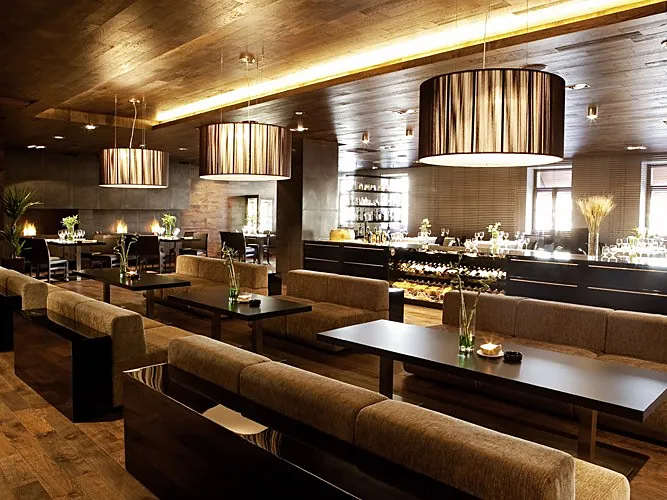 Restaurant with long upholstered benches, dark tables and drum pendants