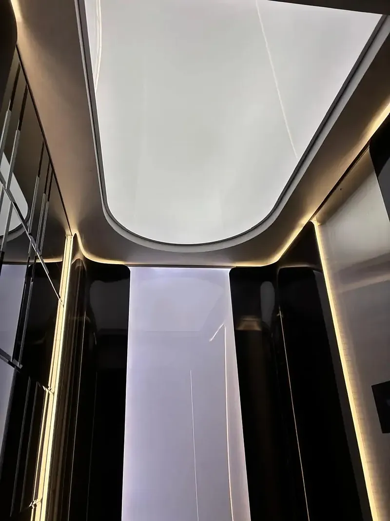 Lit ceiling of a lift car above mirror stainless panels