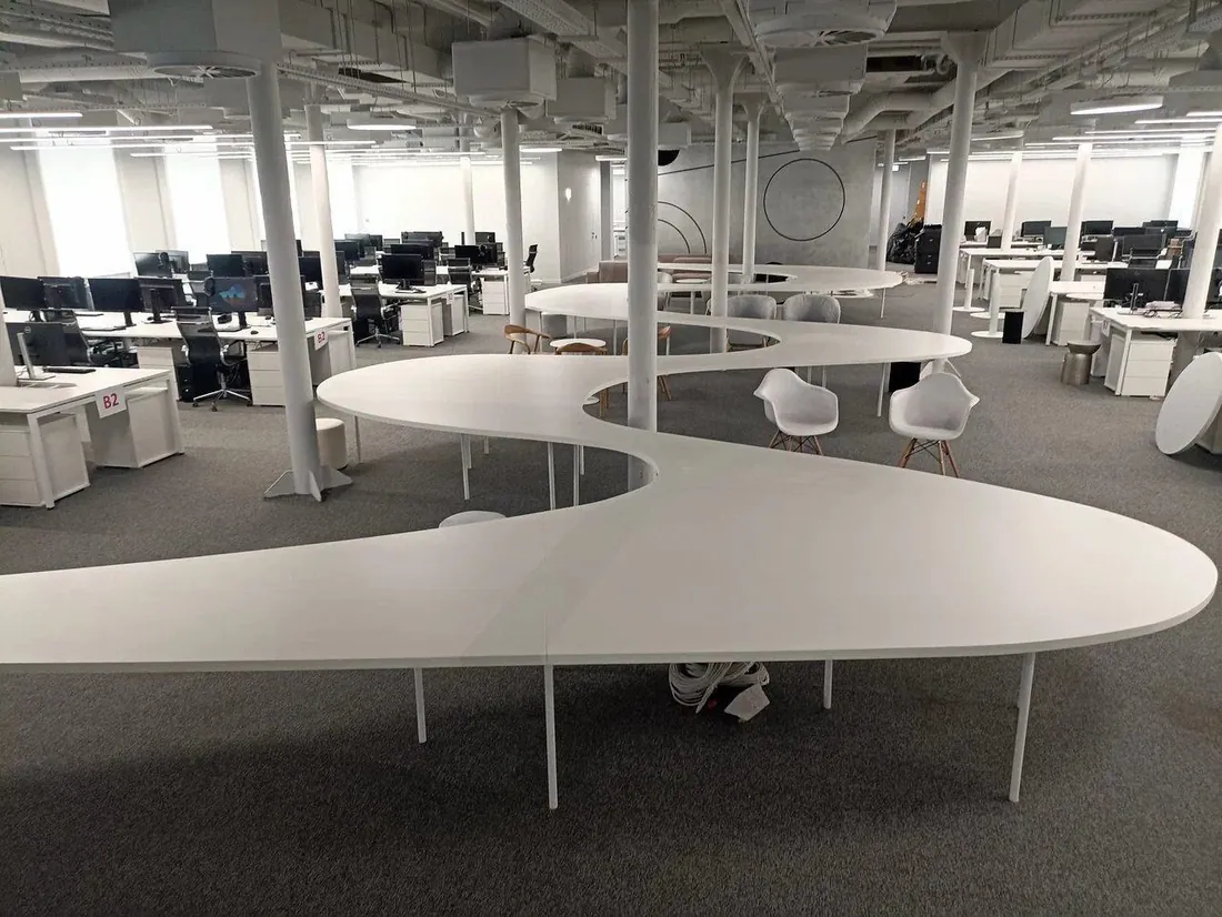 Open-plan office with a long serpentine steel table