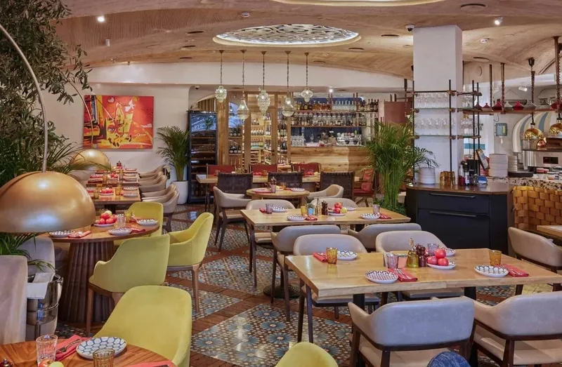 Restaurant hall with yellow and grey armchairs, a bar and arched shelving