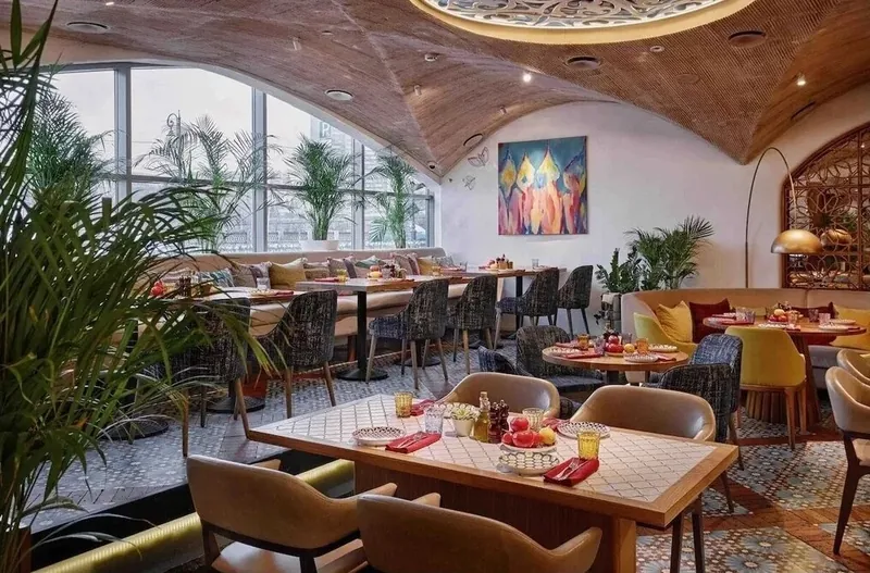 Dining tables with beige armchairs under a timber vault