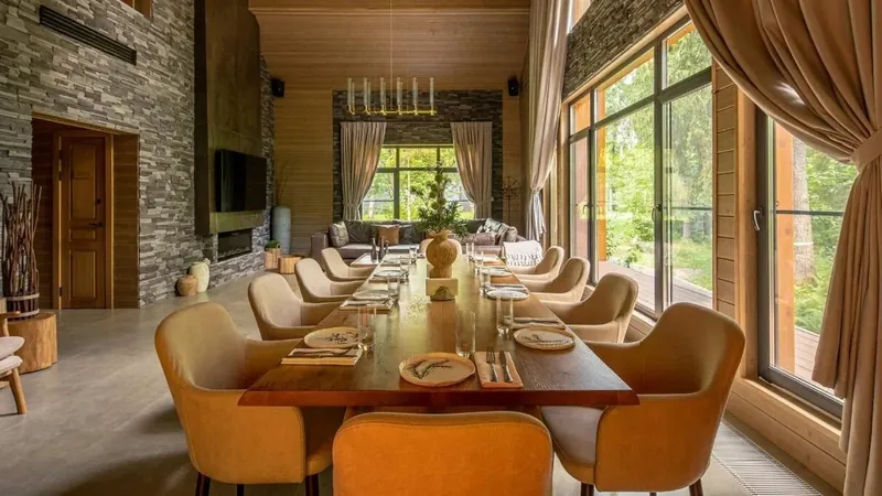 Long dining table with orange armchairs in a timber bath house