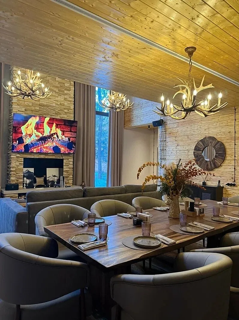 Lounge with grey armchairs, a dining table and an antler chandelier