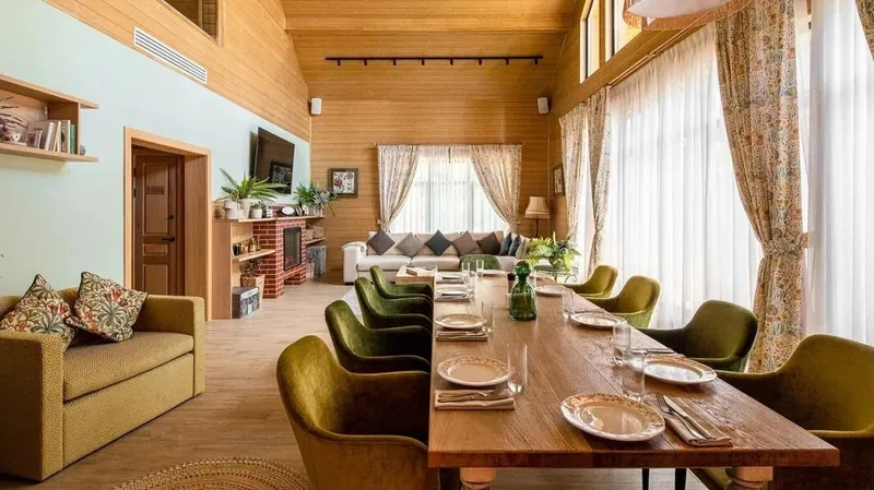 Dining table with olive armchairs in a light timber house