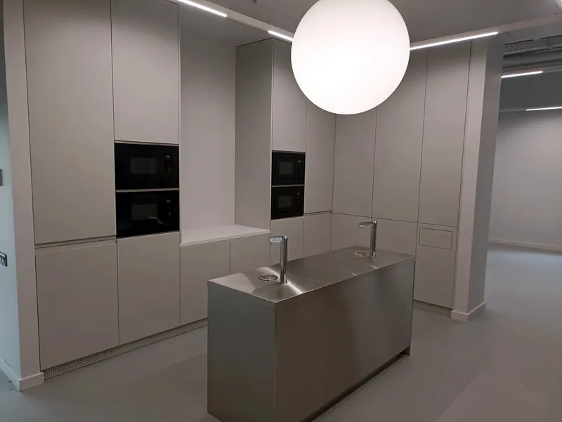 Office kitchen with a brushed stainless island under a globe pendant