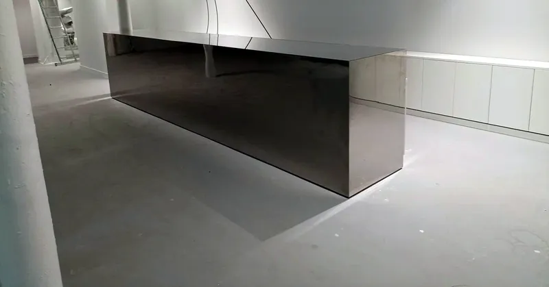 Reception desk clad in mirror-polished stainless steel in a white office