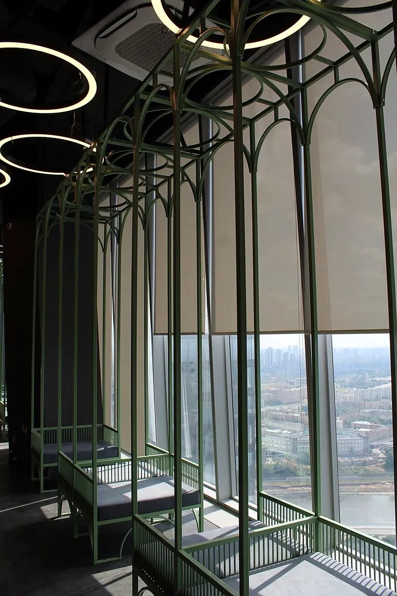 Green steel arches along a floor-to-ceiling window