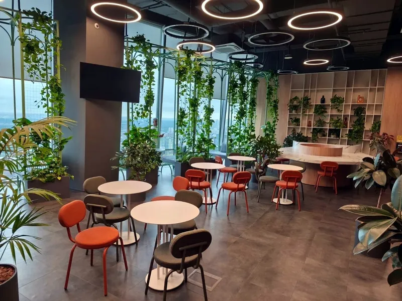Office café with green steel arches, climbing plants and ring lights high above Moscow
