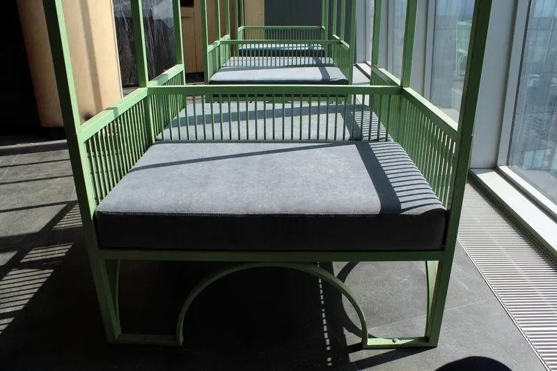 Daybed with a green steel frame and a grey mattress at a panoramic window