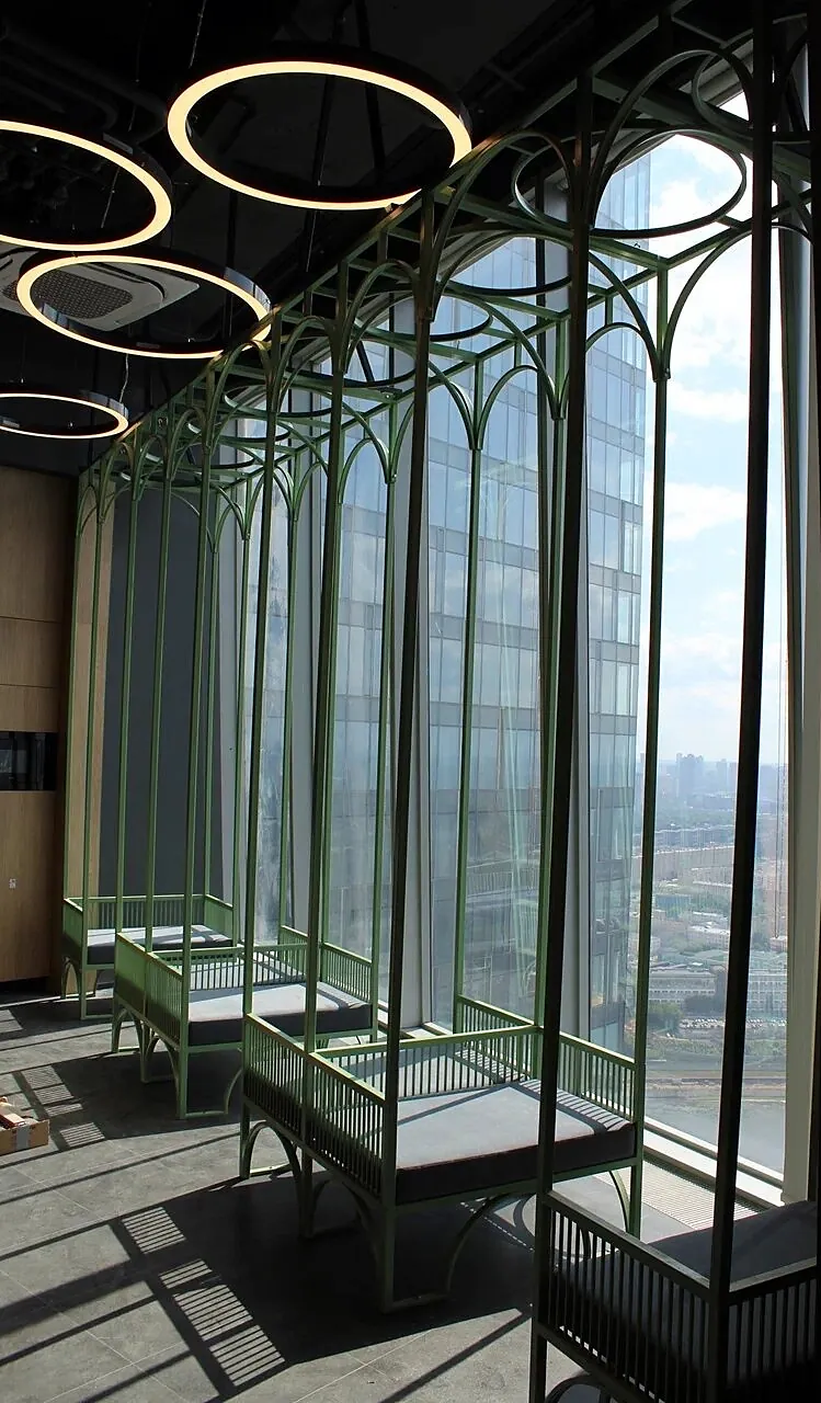Row of daybeds under green arches along the glazing