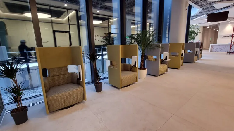 Row of high-back yellow armchairs along a glass facade